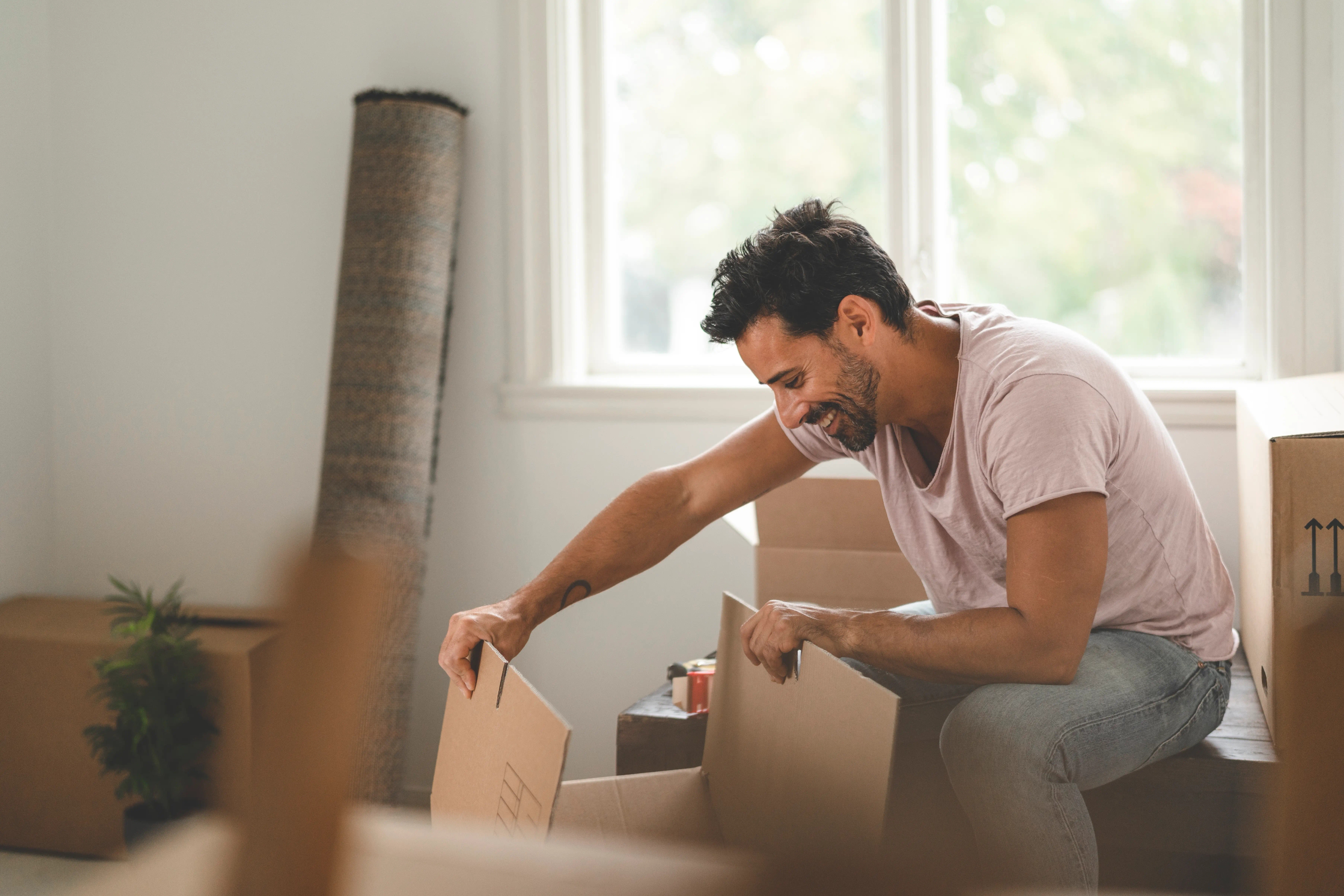Man unpacking a cardboard box in a bright room
